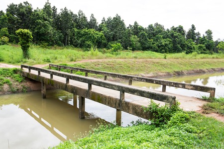 Closeup of concrete bridge and irrigation canal with tree backgroundの写真素材