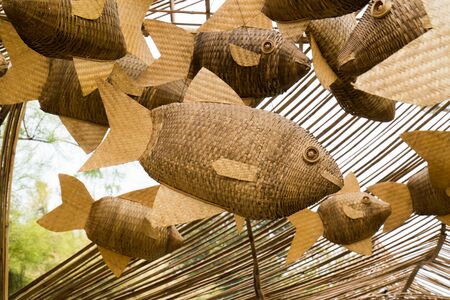 Closeup weave decoration wood fish mobile hanging at public park background. Group woven decorative...