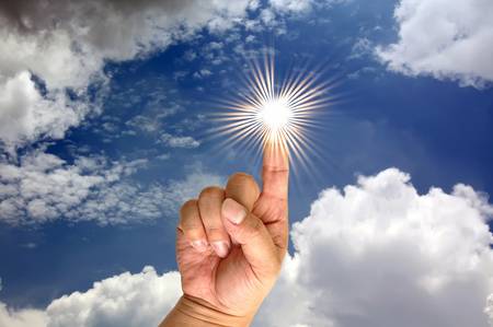 Hand and the sun on blue sky backgroundの写真素材