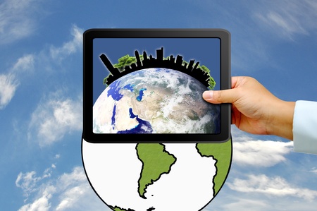 Hand holding tablet PC with city on earth globeの写真素材