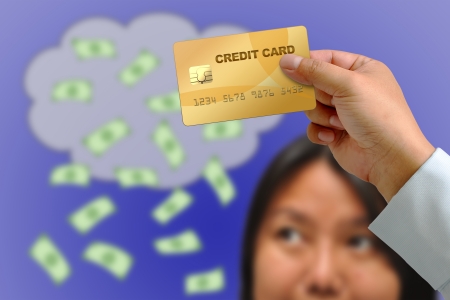 Hand holding credit card with Woman thought Bubbles of Moneyの写真素材