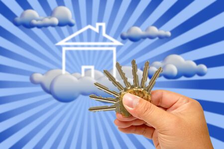 Hand holding keys with house in the backgroundの写真素材