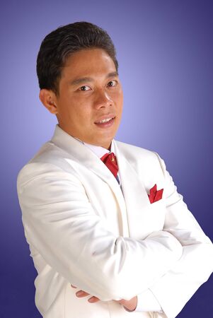 The elegant man in a white tuxedo, studio shot isolated on blue backgroundの写真素材