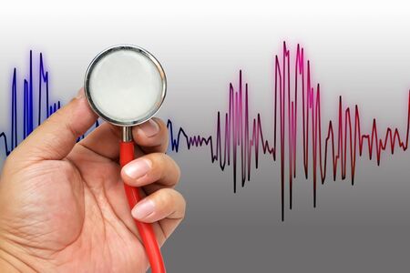 Stethoscope in hand with heart beats cardiogramの写真素材