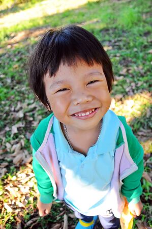 Portrait of asian boy with smile on the grassの写真素材