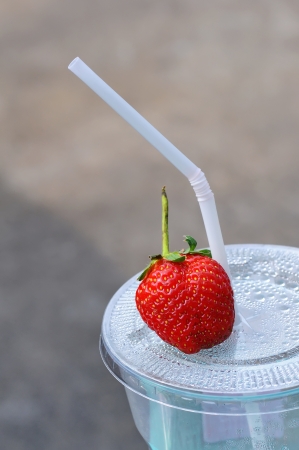 White drinking straw and strawberry on the disposable plastic cupの写真素材