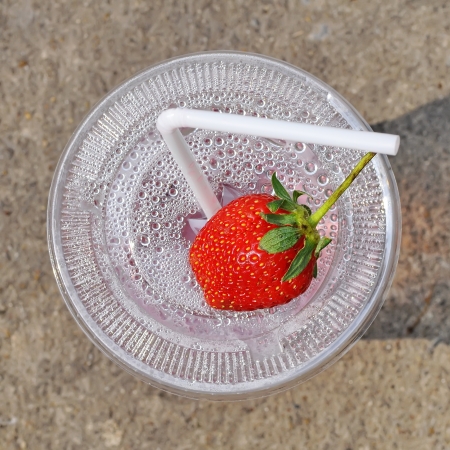 White drinking straw and strawberry on the disposable plastic cupの写真素材