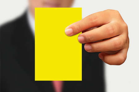 Businessman in suit showing yellow  paper on white backgroundの写真素材
