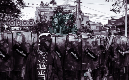 BANGKOK THAILAND  APRIL 10 2010 : Red shirt's security guard stands in front of riot army at Dinso...