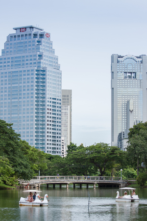 Bangkok, Thailand - August 1, 2015: Swan Boats in Lumpini Park with skyscrapers in the background.のeditorial素材