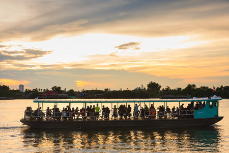 Bangkok, Thailand - June 13, 2015: Backlit Ferry boat takes passengers from Bangna Pier to BangKraChao Pier at sunset, Traveling by boat is a shortcut of traveling in Bangkok (Panning camera)のeditorial素材