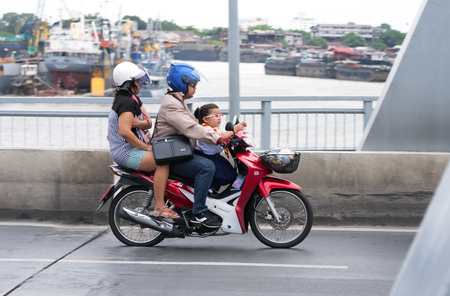 Bangkok, Thailand - June 24, 2015: A family rides on a motorbike on Krungthep Bridge to go back home in the evening, Motorbike is the most fastest vehicles to travel in Bangkokのeditorial素材