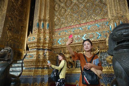 Bangkok, Thailand - October 15, 2018: Chinese tourists taking selfie photo with smartphone at Wat...