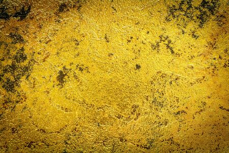 Abstract background texture of stone wall in yellow gold tone. Grunge wall. Cement wall texture and background with copy space for text or image. Dark edgedの写真素材