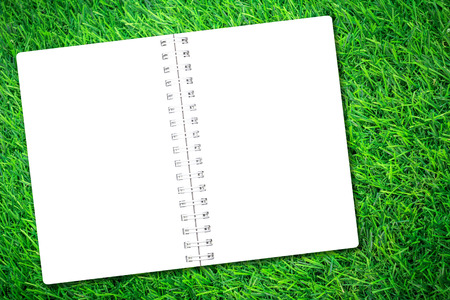 Open notebook paper on green grass background for design with copy space for text or image.の写真素材