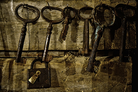 old rusty lock and keys hanging on a wooden wallの写真素材