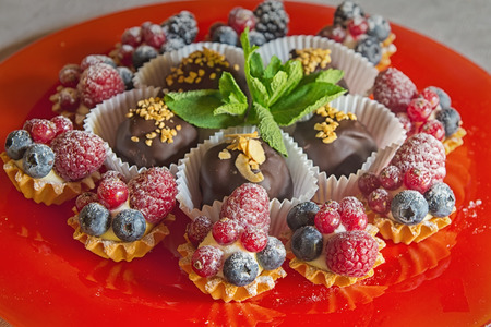 Dessert baked cupcakes with different fruits on a red trayの写真素材