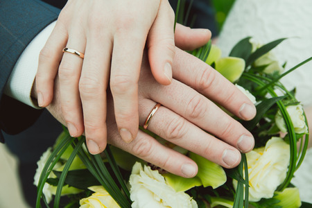 Hands with wedding rings on a bouquet of flowersの写真素材