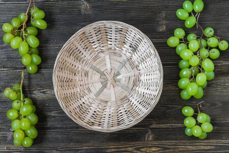 Bright green grapes on a wooden background and basketsの写真素材