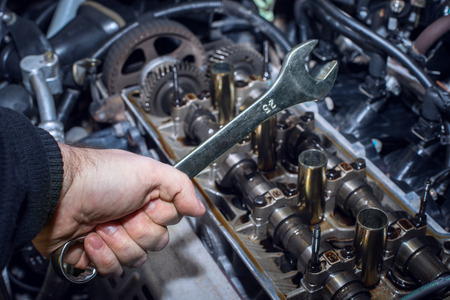 Hand with tool on the motor background with shallow depth of field