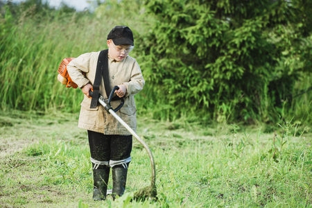Young boy mowing grassの写真素材