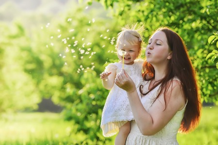 woman and child blowing on a dandelionの写真素材