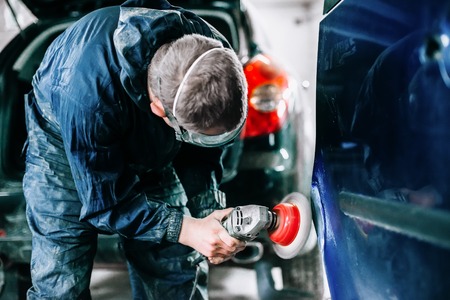 worker processes the surface of the car door