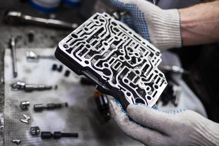 the valve body of the variator of the car in the hands and the details in the background with a shallow depth of fieldの写真素材