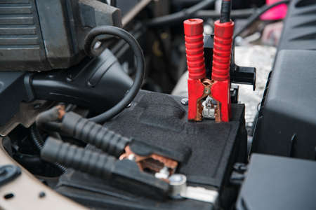 clamping the charger and starting device on the positive terminal of the car battery at shallow...