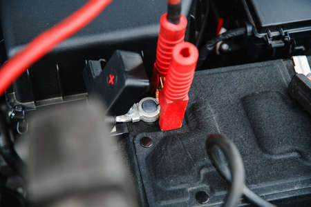 clamping the charger and starting device on the positive terminal of the car battery at shallow depth of fieldの写真素材
