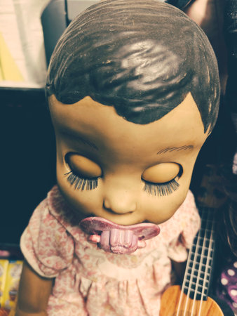 Closeup of a handmade doll with a guitar in the background.の写真素材