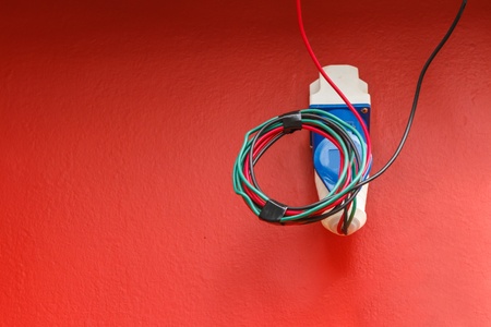 elecrtric cable and electric plug on red wallの写真素材