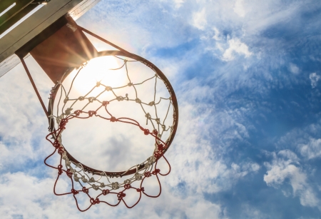 Looking up basketball hoop with a blue sky.の写真素材