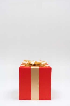 Close-up side view one red paper gift box golden bow ribbon on white background. concept for love