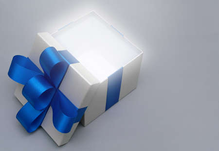 close-up open silver gift box with blue satin bow ribbon soft light glow on grey background.concept for happy surprise father's dayの写真素材