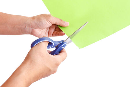 Hand using scissors cuting green paper, isolated on white background