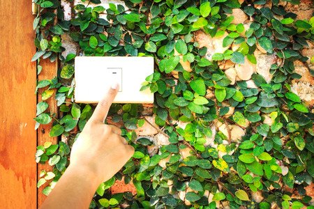 Finger turning white light switch off on with grren ivy