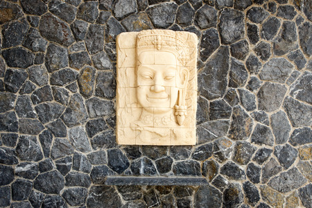 Face of sandstone carving hang on the stone wallの写真素材