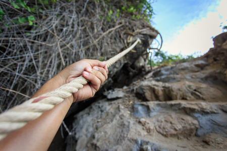 Hand holding rope at the hillの写真素材
