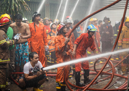 Fireman using water hose to prevent fireのeditorial素材