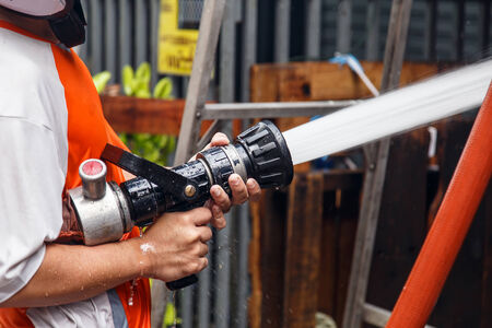 Fireman using water hose to prevent fireの写真素材