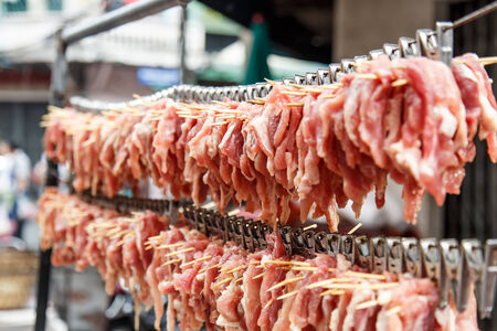 Close up pork hanging on the wooden stick in market, Thailandの写真素材