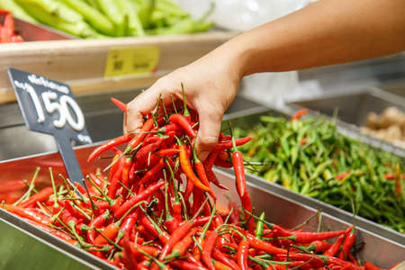 Hand holding chili in department storeの写真素材
