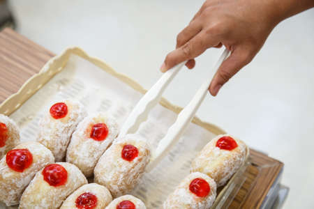 Hand holding Serving kitchen tongs in bakery shop