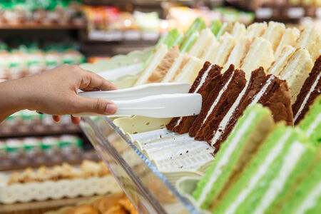 Hand holding Serving kitchen tongs in bakery shopの写真素材