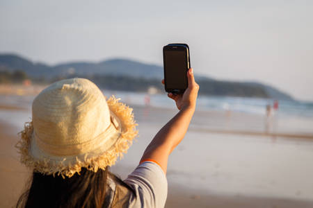 Thai Woman using smartphone at the beachの写真素材