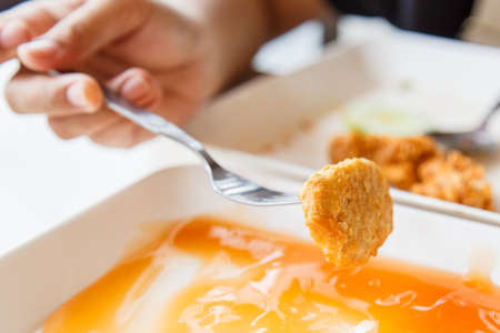 Hand holding Fried  chicken nuggets and eating in the restaurant