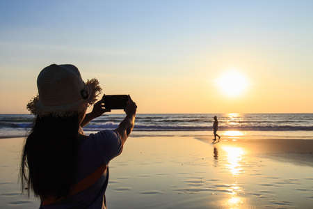 Thai Woman using smartphone at the beachの写真素材