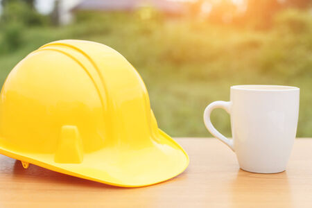 Close up coffee cup and safety helmet on the tableの写真素材