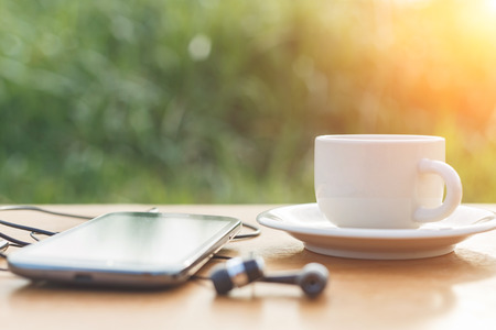 A cup of coffee and smartphone on the tableの写真素材